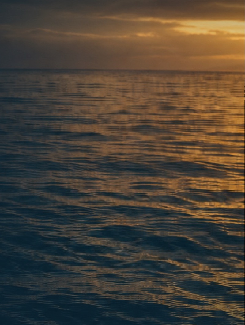 Open water at dusk, the horizon lit gold under low cloud